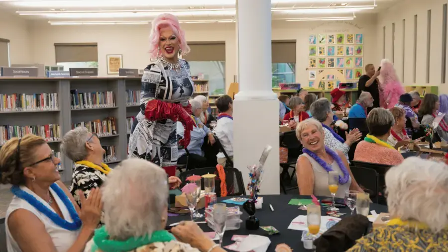 A performer in a newspaper-print outfit interacts and laughs with event attendees.